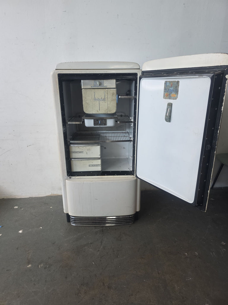 Antique Hotpoint fridge from the 1930s, featuring a retro design and aged, complete interior; sold as is.
