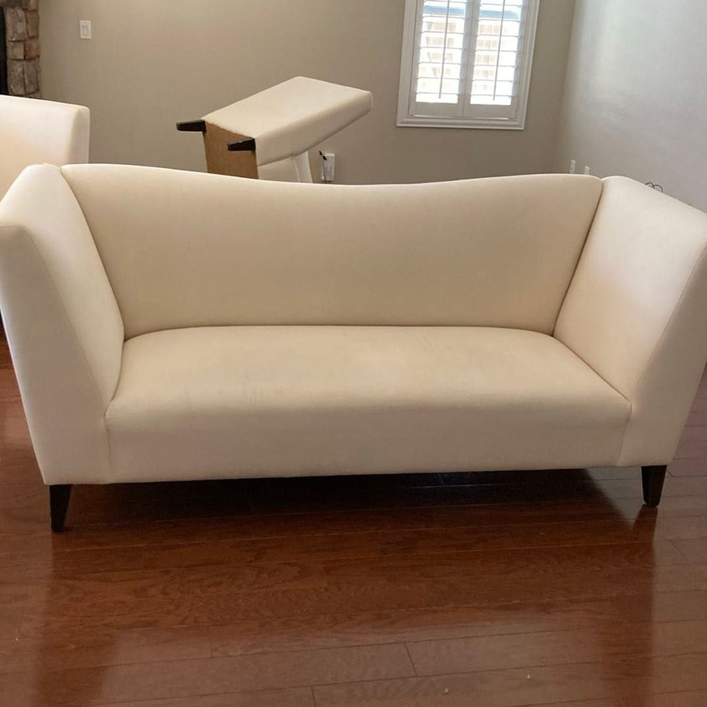 Shabby Chic cream loveseat with curved back and wooden legs, seating two comfortably in any room.