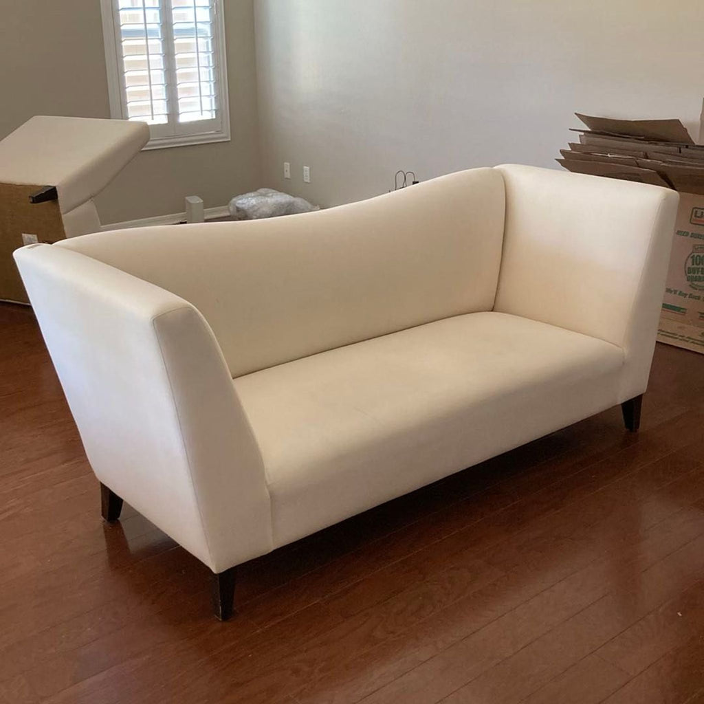 Cream-colored Shabby Chic loveseat featuring gently curved backrest and solid wood legs, modern and elegant.