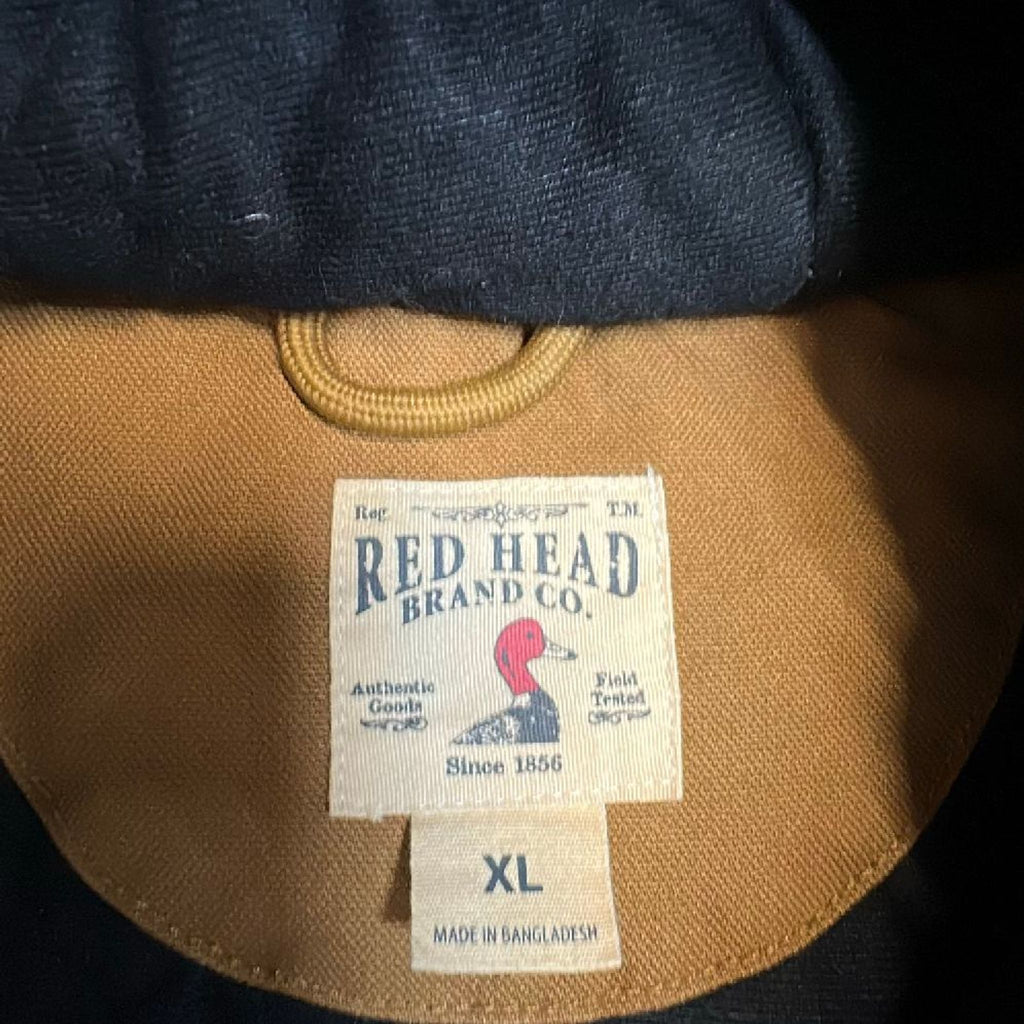 2. Close-up of RedHead Brand Co. label inside a brown men's jacket, showing size XL and logo.