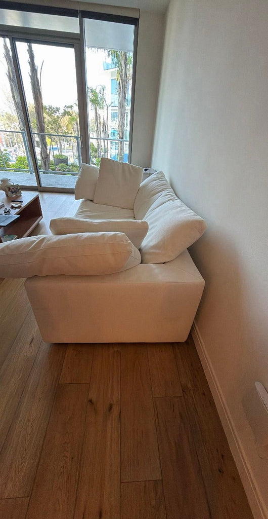 3. Spacious white 3-seat Restoration Hardware couch with broad arms, positioned near a window in a bright room.