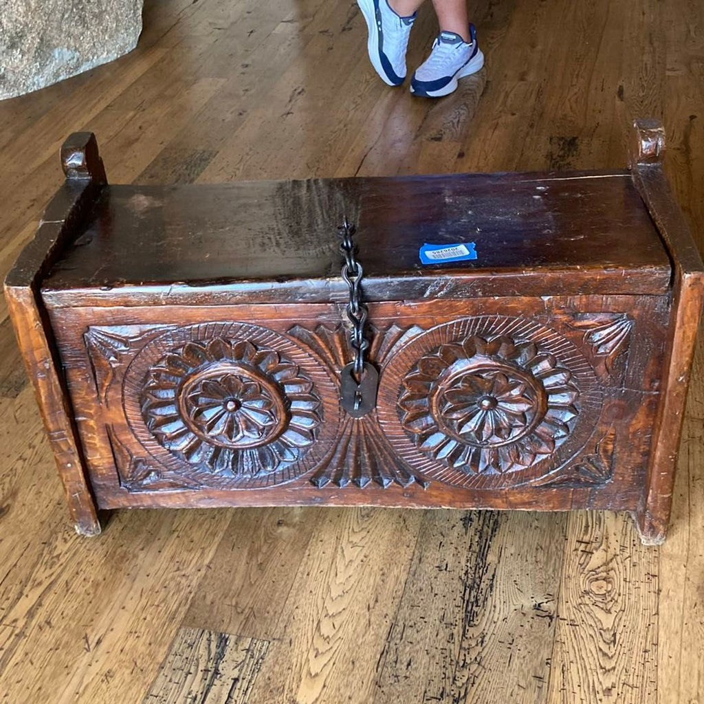 2. Carved wood trunk from the Trunk category, featuring decorative designs, chain and lock, on rustic hardwood flooring.