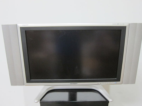 1. Front view of a Sharp Aquos LC-26GD4U LCD TV with integrated side speakers on a silver stand.  