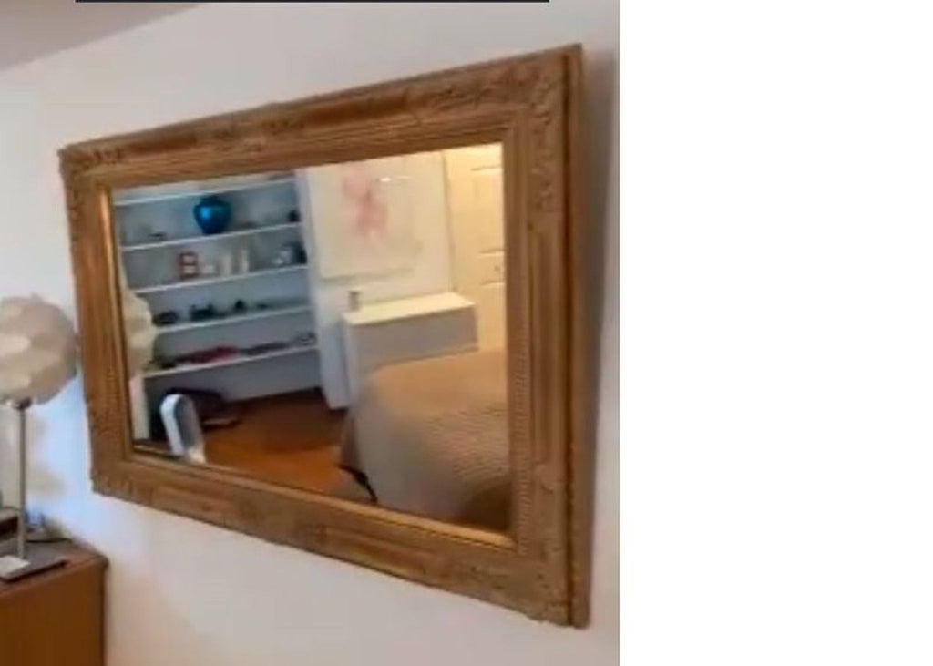 1. Ornate gold-framed wall mirror reflecting a bedroom interior with shelves, bed, and decor visible in the glass.