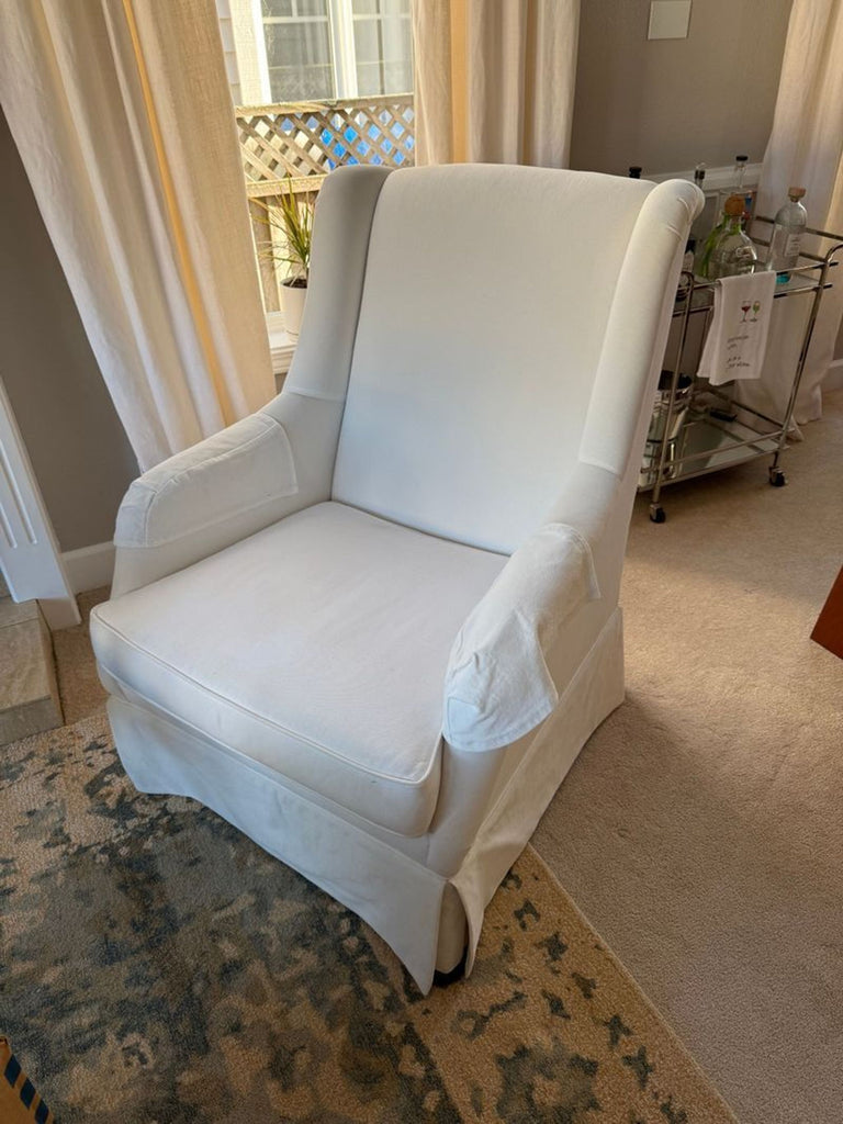 3. Elegant Reperch lounge chair, white with smooth upholstery, positioned by a window with draped curtains.