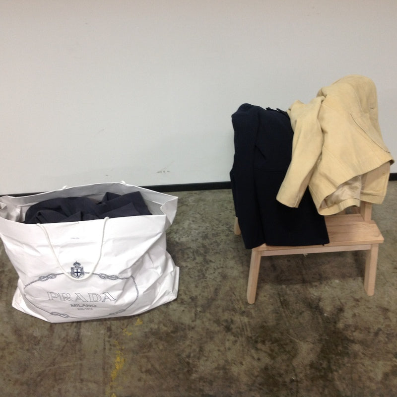 2. Large white bag of women's Reperch jackets and pants beside a bench with folded outerwear.  