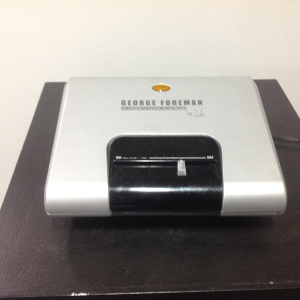 George Foreman Grilling Machine small appliance shown closed with a silver top and adjustable heat setting.