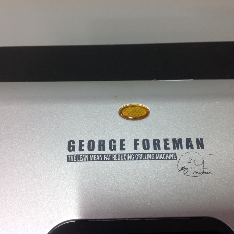 Close-up of George Foreman Grilling Machine branding and indicator light, showing the product logo on the lid.