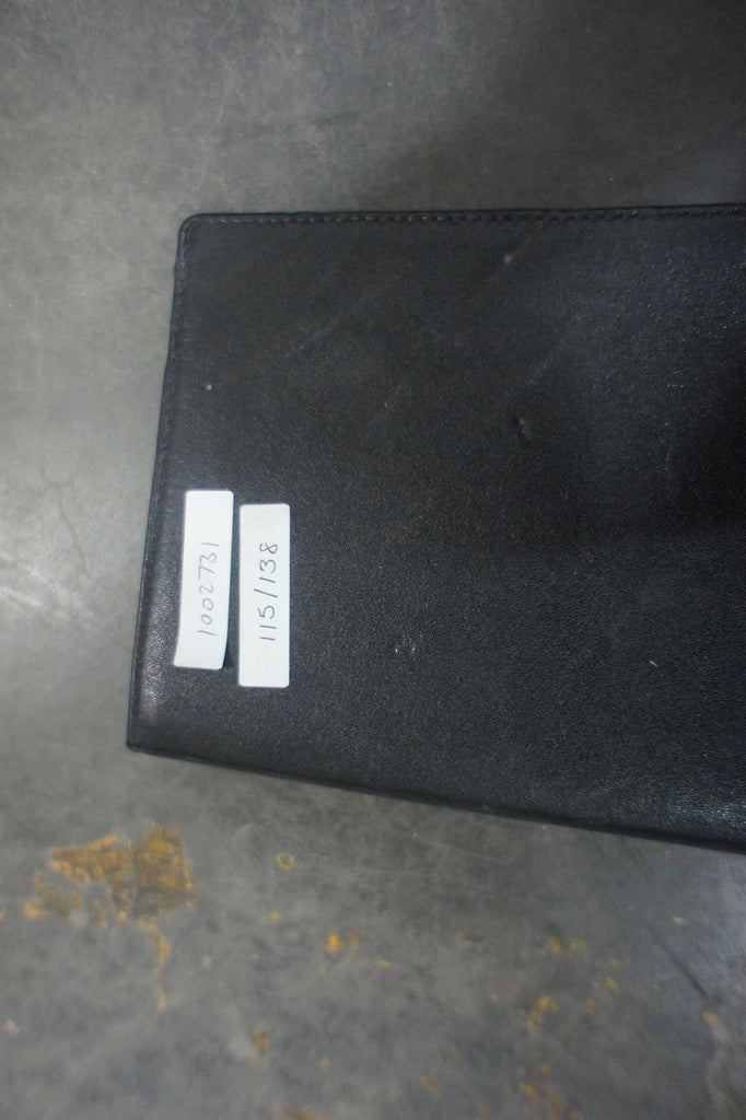 2. Close-up of a black Amazon Kindle cover with two white inventory labels, placed on a gray surface.