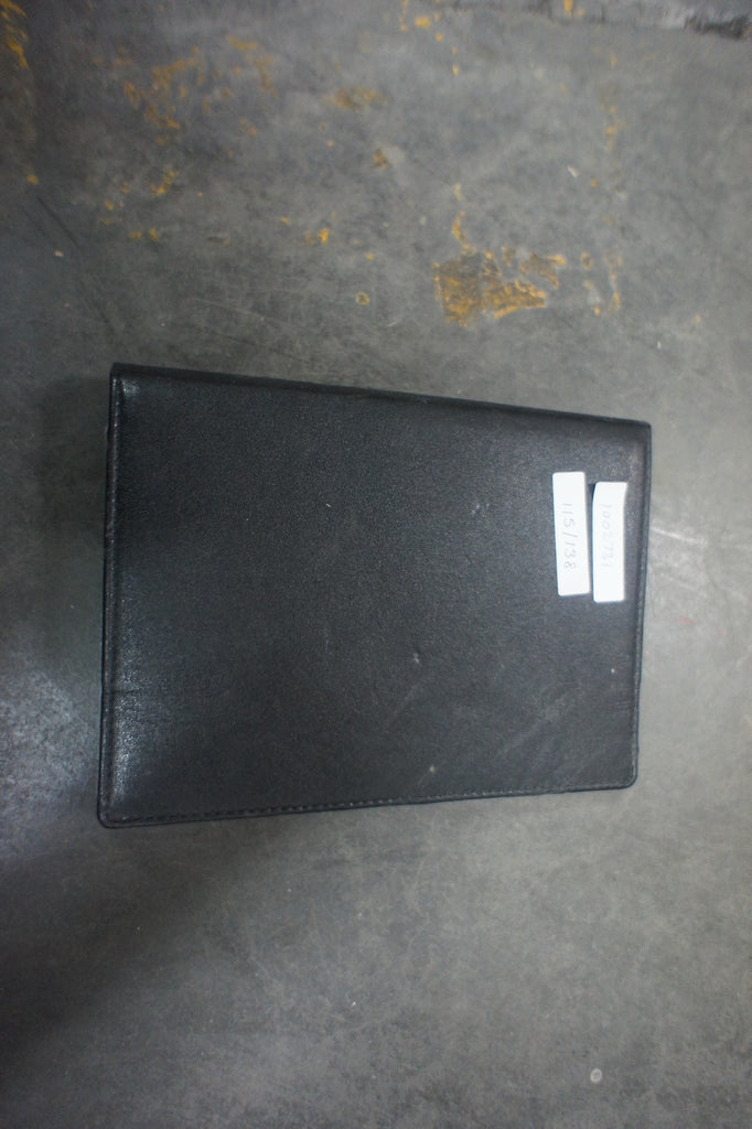 3. Closed black Amazon Kindle case with inventory stickers, photographed from above on a concrete floor.