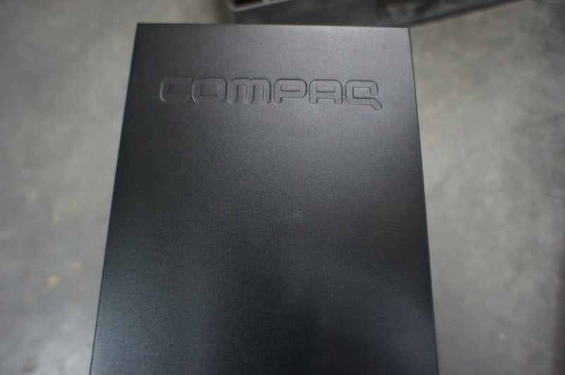 3. Embossed COMPAQ logo on the matte black side panel of a Compaq CQ5205Y desktop PC.