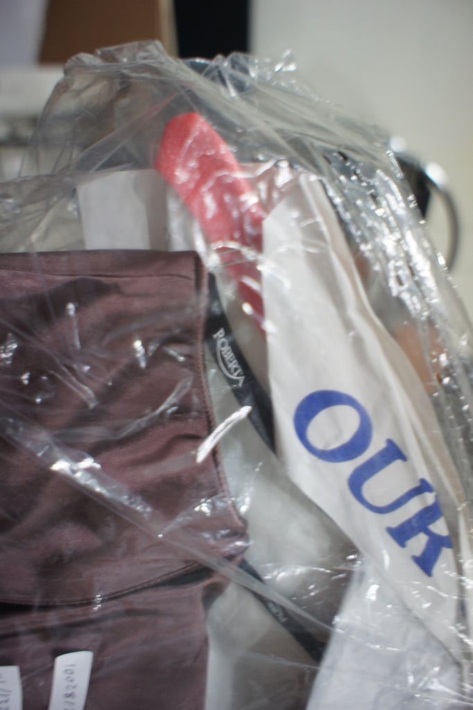 3. Top view of Roberta brown dress on hanger, partially obscured by plastic and packing materials.