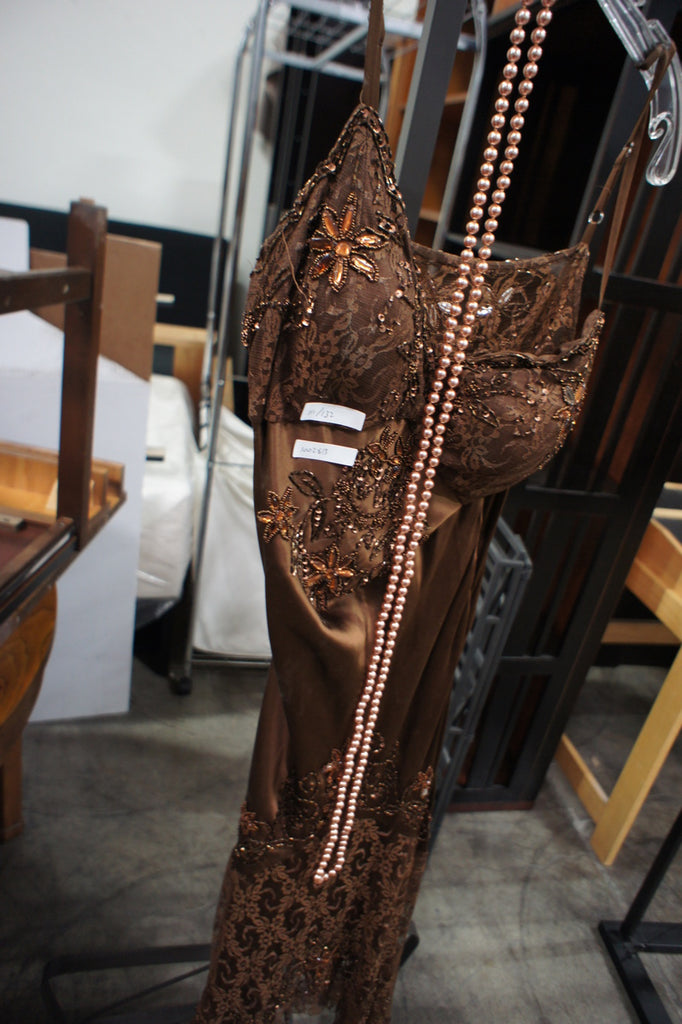 3. Full view of Bicici brown lace women's dress accessorized with a long strand of pearls.