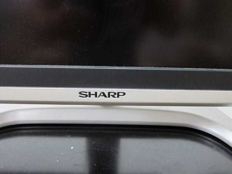 3. Sharp brand logo displayed on the bottom bezel of a Sharp Aquos television above the stand.