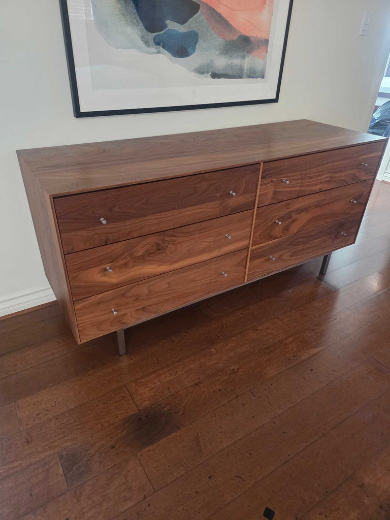 2. Angled view of a clean-lined walnut dresser by Room & Board, featuring sleek metal handles and sturdy legs.