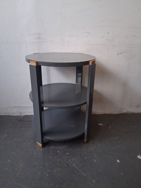 Round gray side table with brass accents, two shelves, modern design by Andrew Martin for Sonder Living.