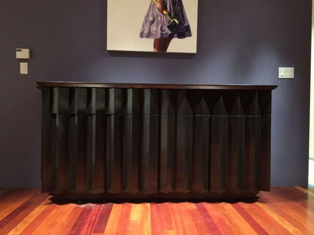 3. Frontal view of Derepage Design credenza featuring angular, sculpted doors and dark finish in a modern space.