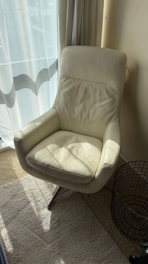 Ikea high-back white leather-look lounge chair with swivel base, photographed from the front in a modern setting.  