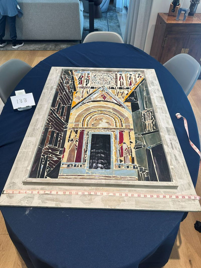 2. Mosaic art of an ornate doorway is displayed on a blue table, with a tape measure showing its width.