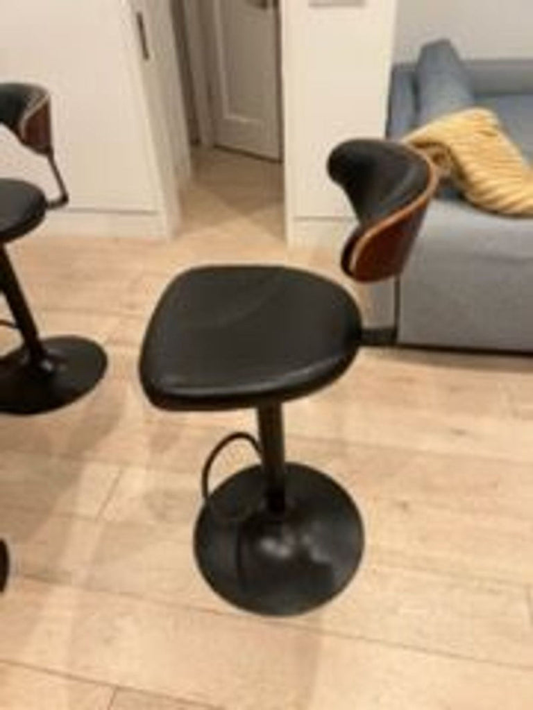 1. Modern Ashley Furniture bar stool with black seat, low backrest, and metal base, ideal for contemporary interiors.