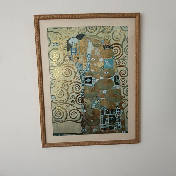 1. Framed print of a golden, patterned artwork with two embracing figures, displayed on a wall.