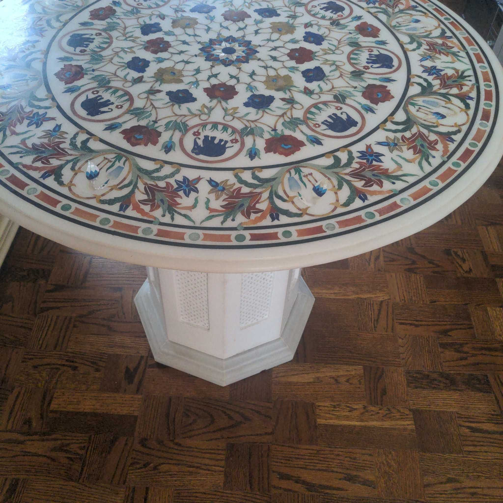 1. Round side table with intricate floral inlay design on top, set on a white octagonal base on wooden floor.