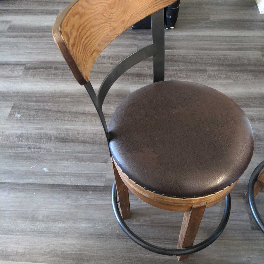 2. Single brown bar stool with a curved wooden backrest, padded round seat, and metal footrest ring.