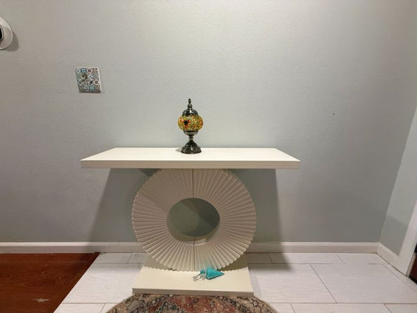 1. Modern white console table with a sculptural circular base, placed against a light wall with small decor.