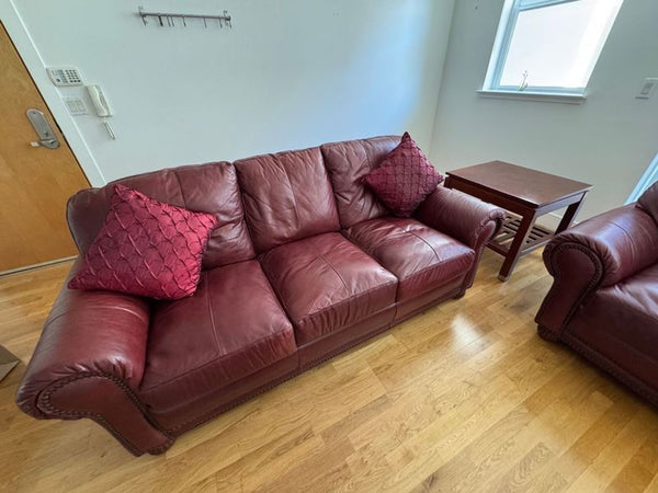 1. Reperch 3-seat maroon leather sofa with plush cushions and two decorative pillows in a bright living room.  