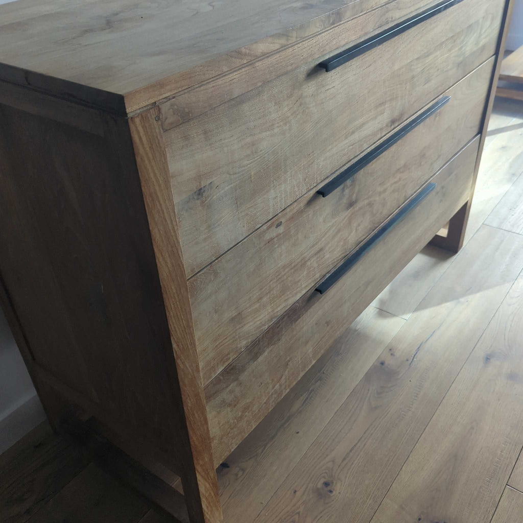 1. Angled close-up of a Crate and Barrel wooden dresser with three drawers and sleek black handles.