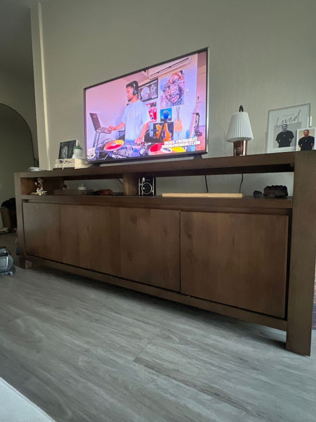 1. Living Spaces entertainment center in dark wood, with a TV and decor, shown in a modern living room setting.