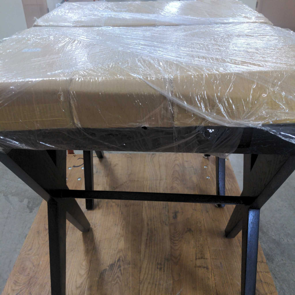 1. Two side tables with black "X" legs and square tops, wrapped in protective plastic, placed on a wooden surface.