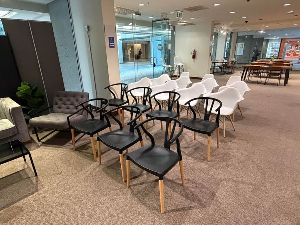 1. Rows of modern black and white dining chairs with wooden legs arranged in a spacious meeting room.