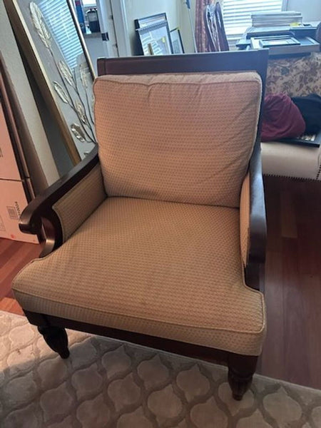 1. Lounge chair with wooden frame and beige textured cushions, shown in a home setting surrounded by decor.