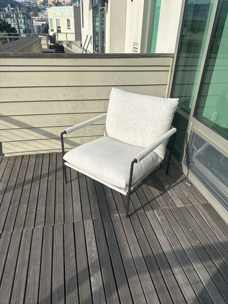 1. Modern Crate and Barrel lounge chair with light cushions and slim black frame on an outdoor wooden deck.