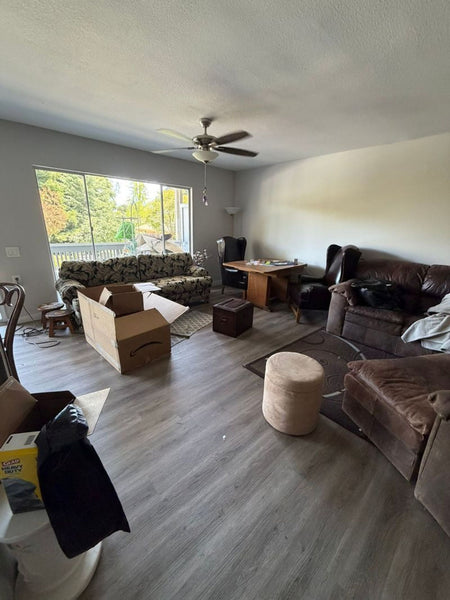 Spacious lounge with large windows, containing Kroehler furniture including a brown leather armchair and sofa.  