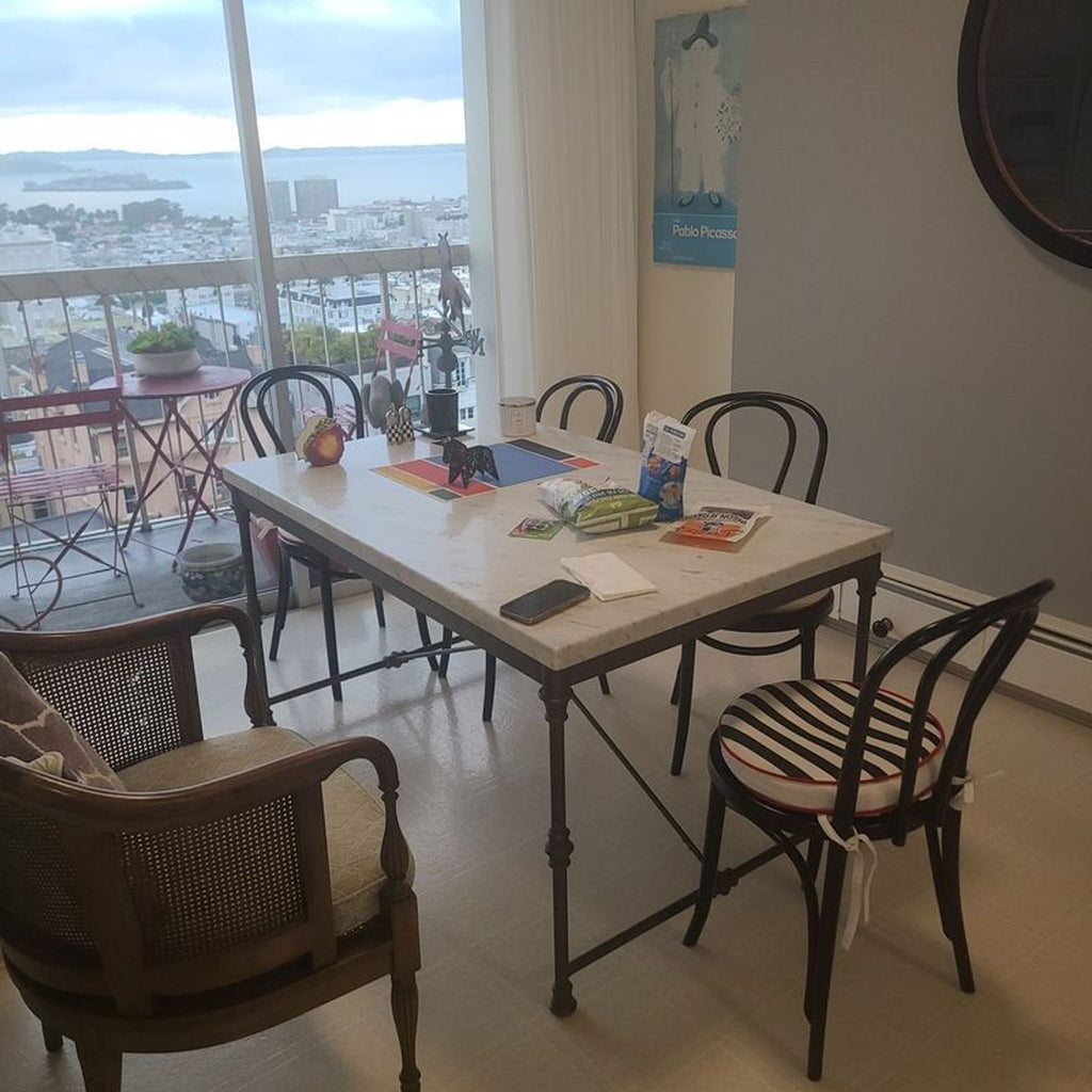 1. Crate and Barrel dining set with a marble table and four black chairs, two with striped cushions, in a home setting.