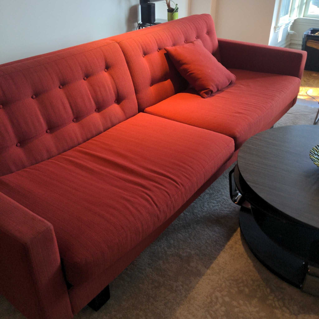 3. Angled view of a red Room & Board 3-seat sofa with tufted detailing and a single red throw pillow.