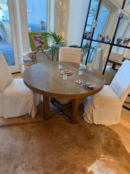 1. Reperch round wooden dining table in a modern dining area, paired with two fabric-covered chairs.