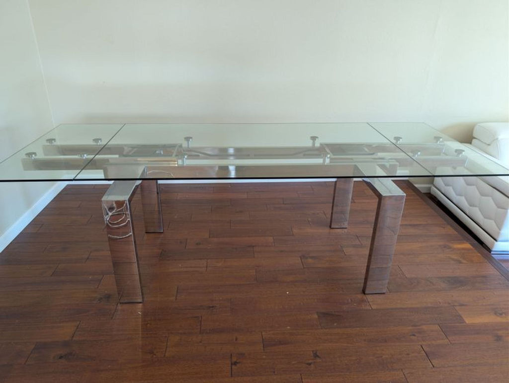 1. Modern coffee table with a clear glass top and sturdy metal legs, on a wooden floor in a living room.  