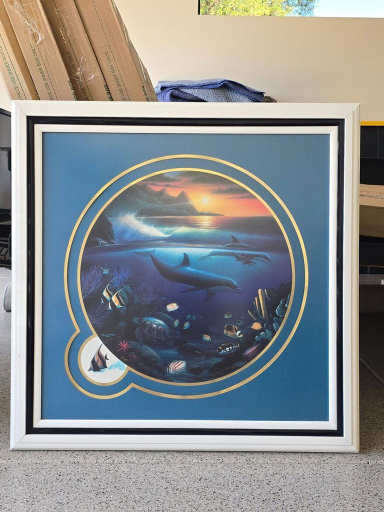 Glossy white-framed circular print shows a lively sunset ocean view with dolphins and fish; ideal for nature art lovers.