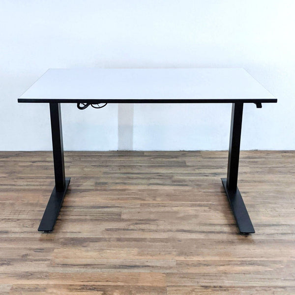 Motorized white desk with black steel frame, shown on wooden floor.  
