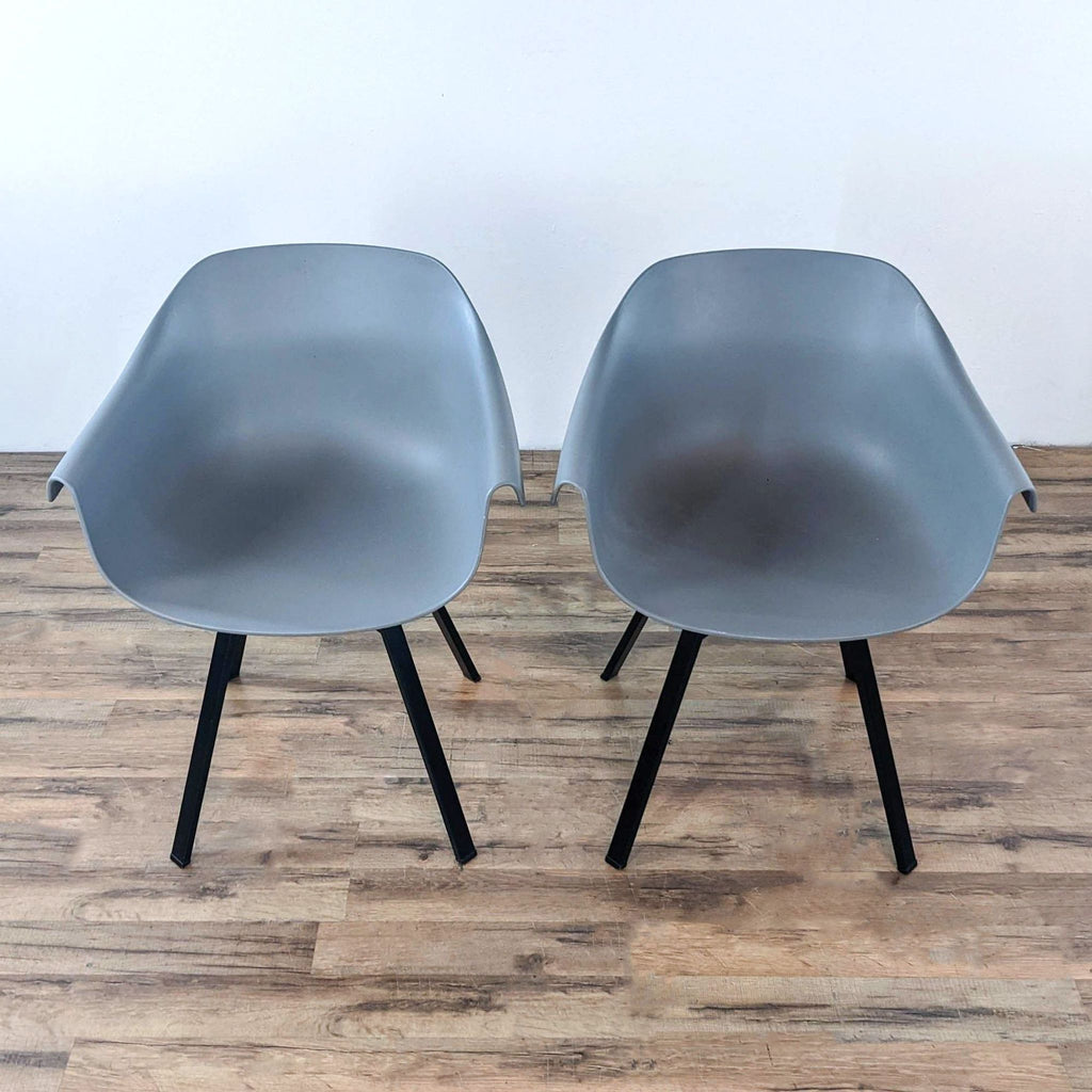 Pair of gray swivel chairs with black legs on a wooden floor.