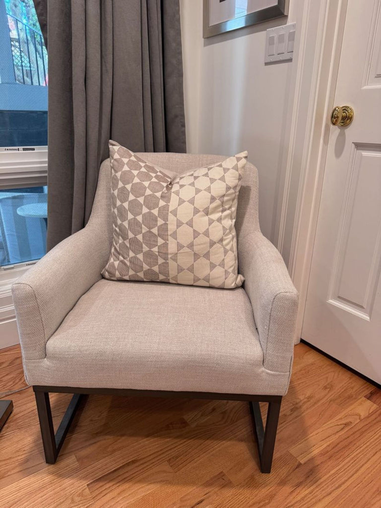 1. E&E Co. lounge chair in light beige fabric with a patterned cushion, set on wooden flooring.