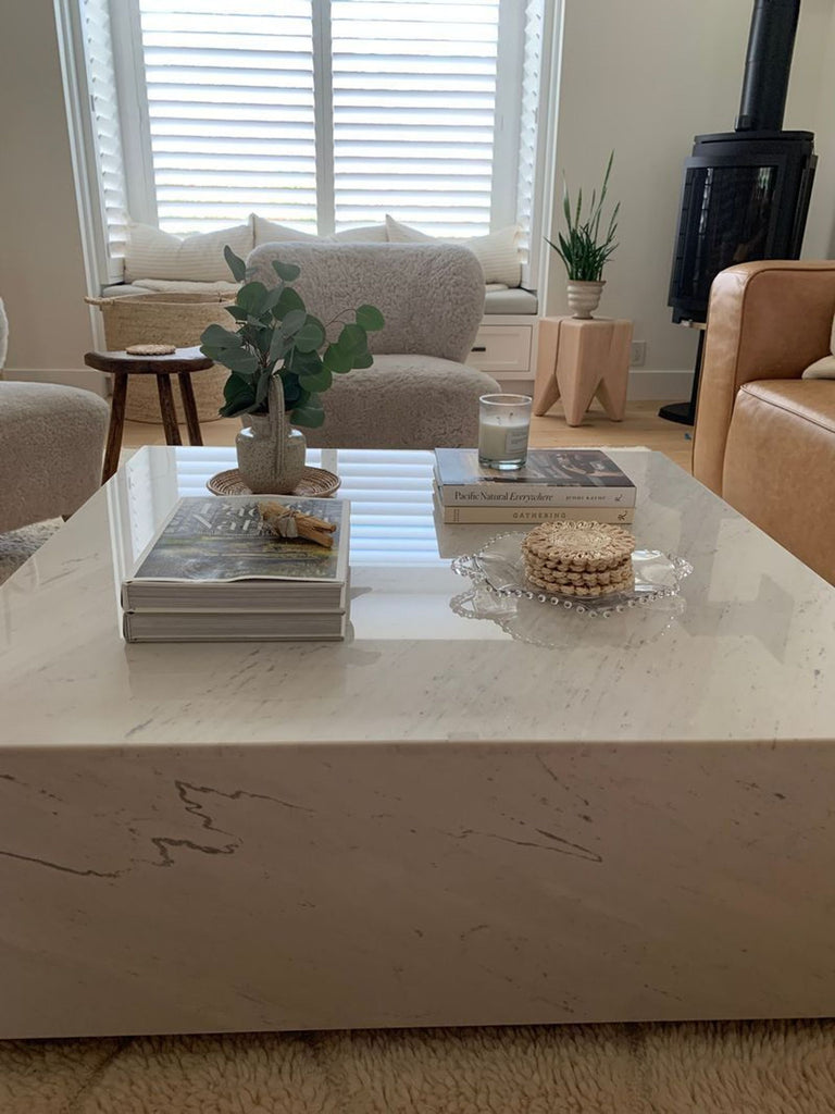 3. Modern living room with a square marble Rove Concepts coffee table holding books, a plant, and a candle.