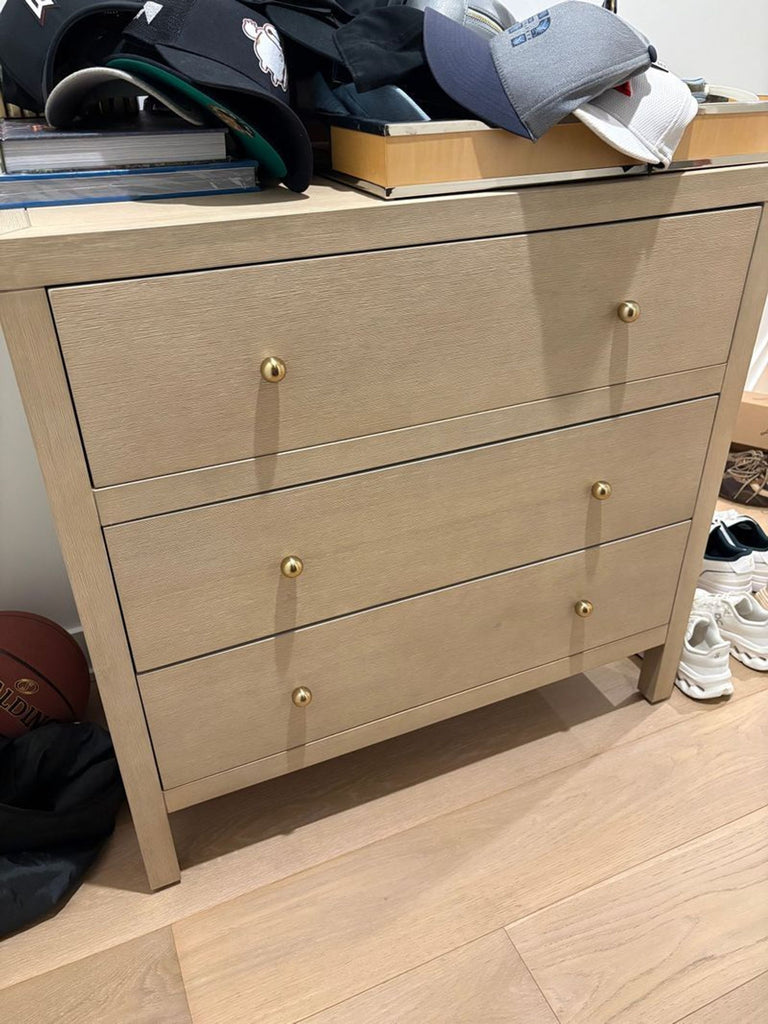 1. Light wood three-drawer dresser by Butler Specialty Company, with gold knobs, used as storage for hats and books.