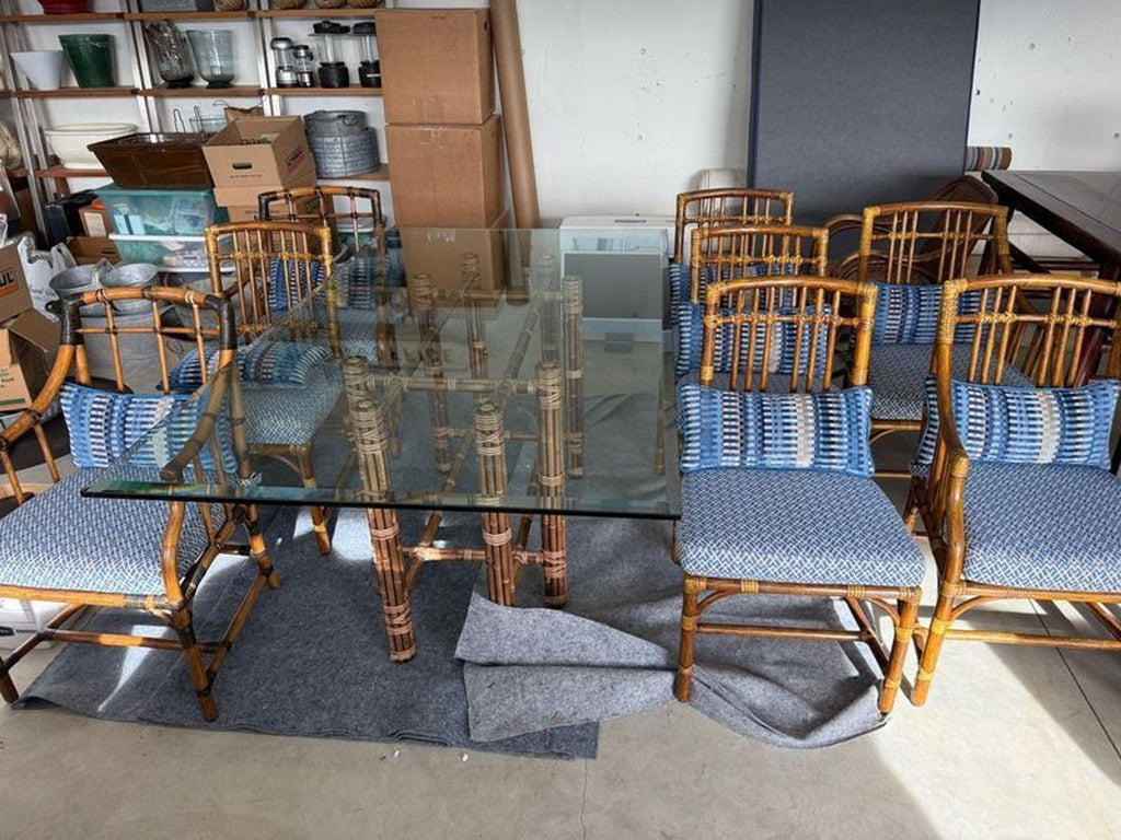1. McGuire San Francisco dining table set with glass top and eight bamboo chairs with blue cushions.