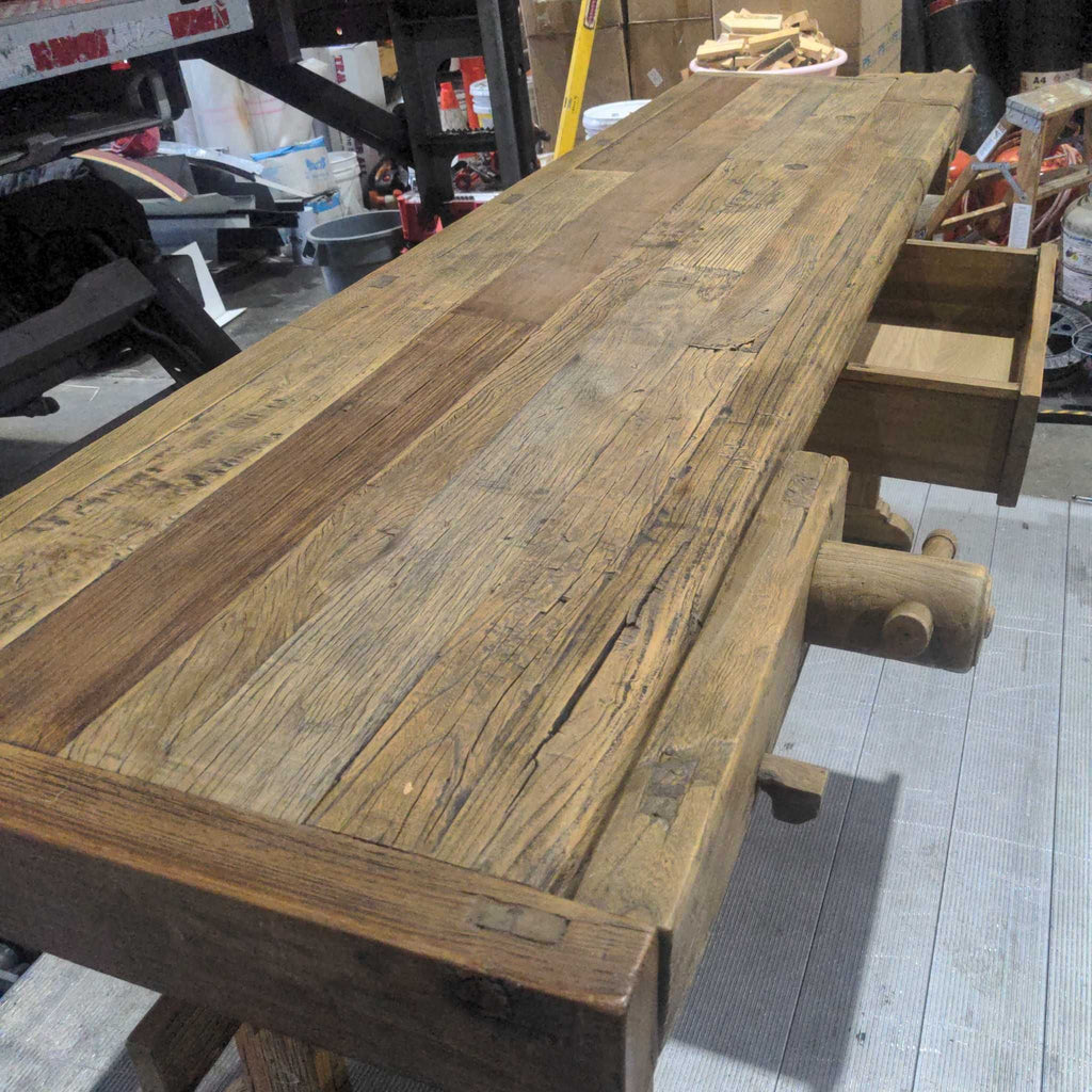 1. Antique wooden workbench with visible grain, open drawers, and a wooden vise, placed in a workshop setting.