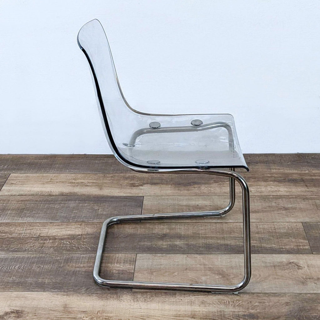2. Side profile of a clear acrylic dining chair by Reperch, featuring a modern chrome base.