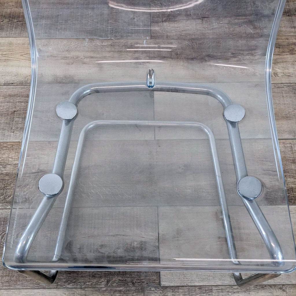 3. Close-up of clear acrylic seat and chrome base details on a Reperch dining chair.